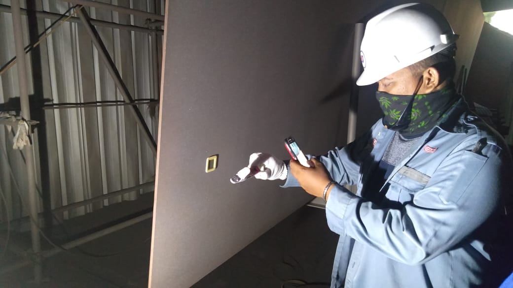 Seorang Coating Inspector sedang melakukan inspeksi ketebalan cat menggunakan alat ukur pada proyek industri berskala besar