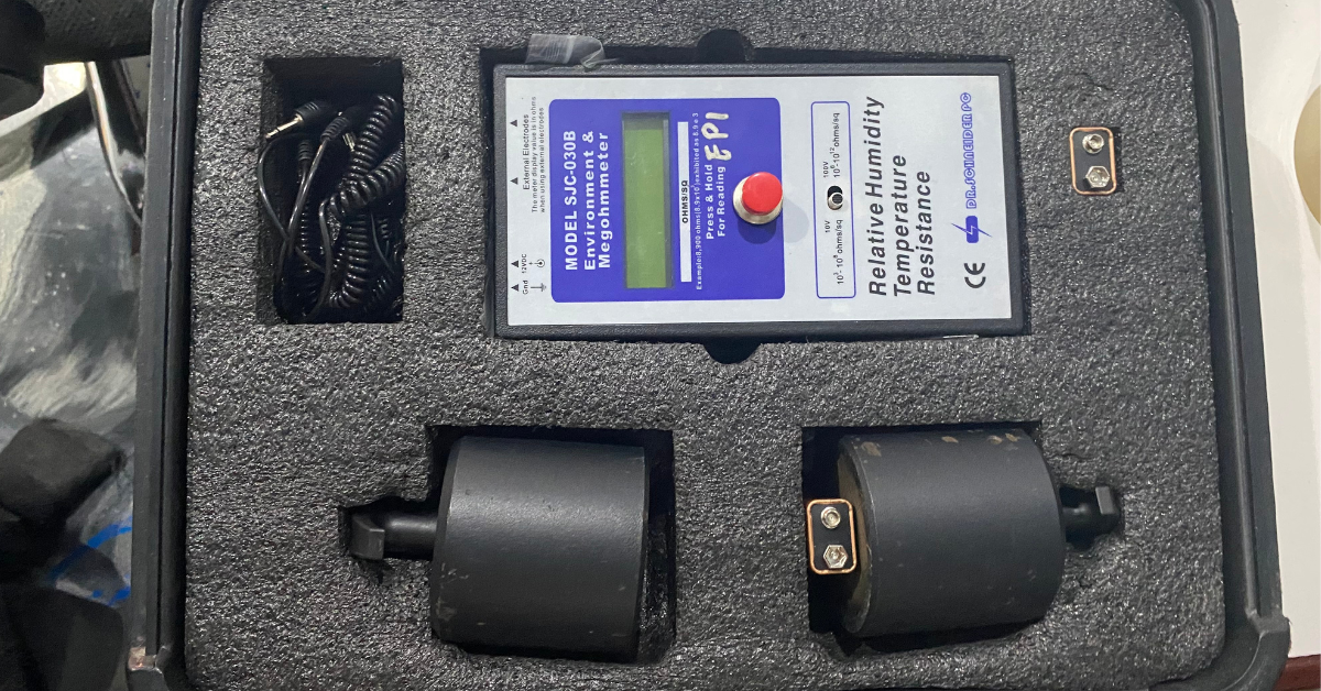 Alat ukur ESD Megohmmeter digital model SJC-030B dalam kotak pelindung, lengkap dengan dua probe elektroda bundar, kabel penghubung, dan layar digital untuk pengukuran resistansi, kelembaban, dan suhu.