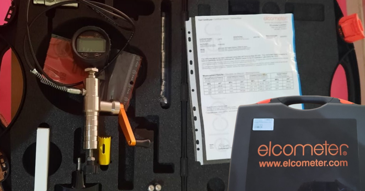 Peralatan pull off test Elcometer lengkap dalam hardcase, termasuk gauge digital, pompa hidrolik manual dengan tuas oranye, aksesori alat, serta sertifikat kalibrasi resmi.