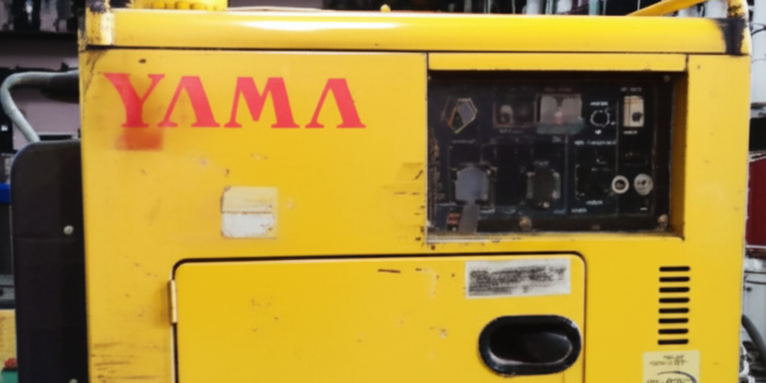 Generator diesel portabel YAMA berwarna kuning dengan panel kontrol